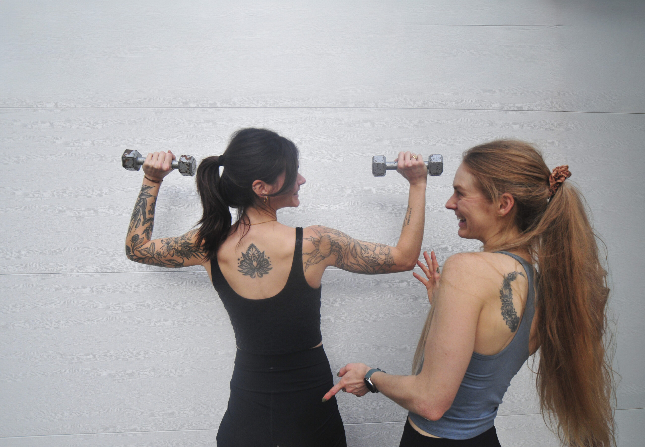 Personal training with bekah two women standing next to each other, one holding dumbbells in cactus pose position the other smiling and gesturing at her form
