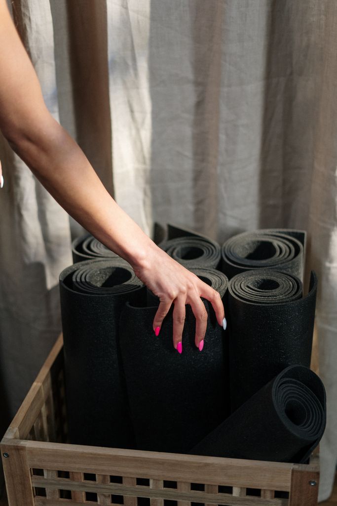 Personal training with bekah Close-up of a hand selecting a yoga mat from a basket in a yoga studio.